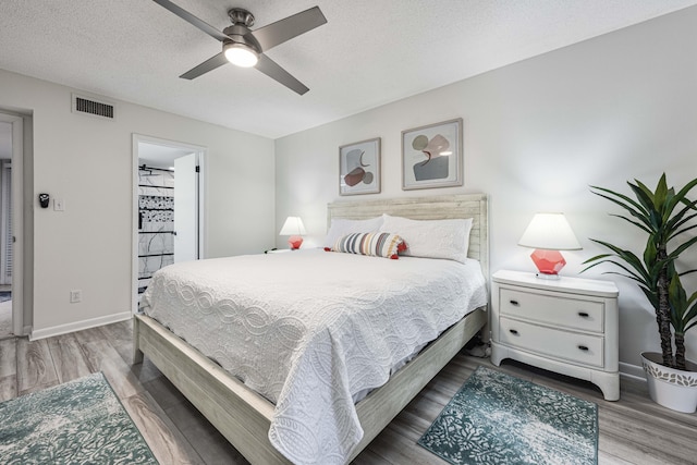 bedroom with ceiling fan, a textured ceiling, and hardwood / wood-style flooring