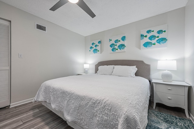 bedroom with ceiling fan, a textured ceiling, and dark hardwood / wood-style flooring