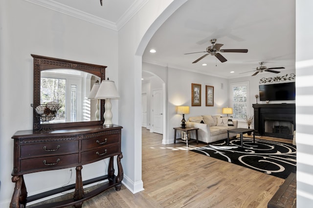 living room featuring crown molding, a wealth of natural light, ceiling fan, and light hardwood / wood-style flooring