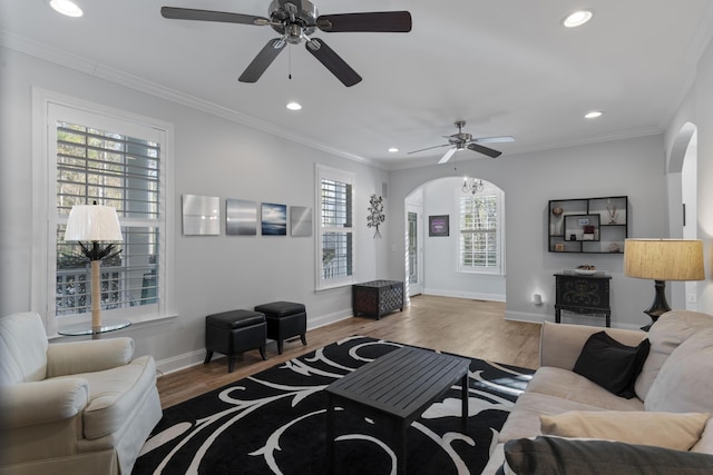 living room with hardwood / wood-style flooring, ceiling fan, and ornamental molding