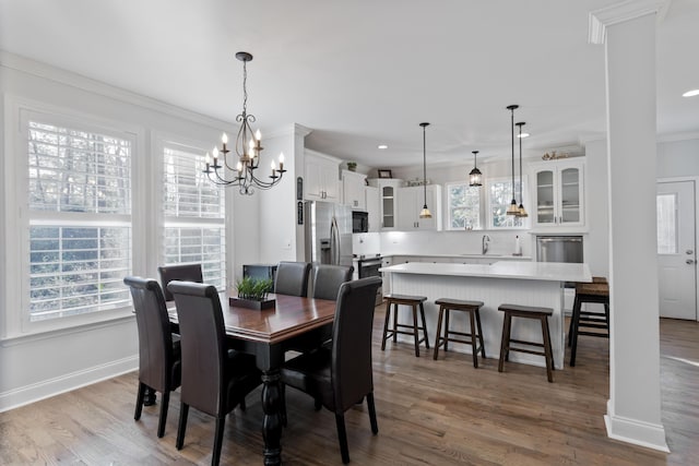 dining area featuring crown molding, sink, an inviting chandelier, and light wood-type flooring