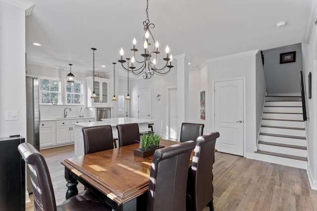 dining space with ornamental molding, sink, and light hardwood / wood-style flooring