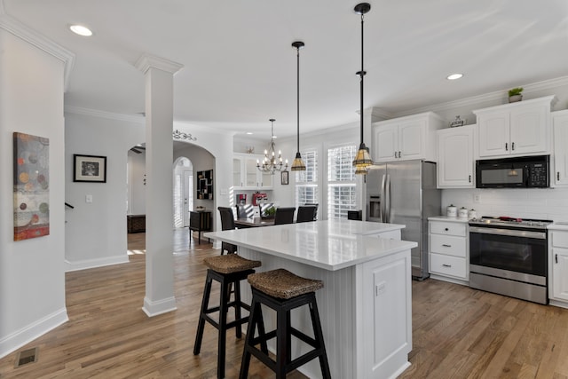 kitchen featuring decorative light fixtures, a center island, stainless steel appliances, decorative backsplash, and white cabinets