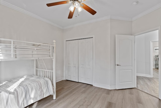 bedroom with crown molding, ceiling fan, light wood-type flooring, and a closet