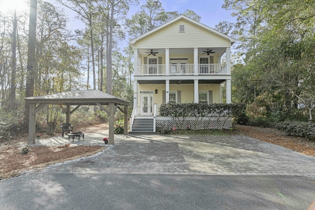 view of front of property with a gazebo, a balcony, an outdoor fire pit, ceiling fan, and covered porch