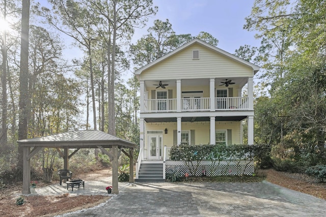 view of front of home with a balcony, covered porch, a fire pit, ceiling fan, and a gazebo