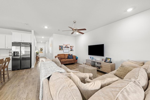 living room with ceiling fan and light hardwood / wood-style flooring