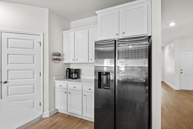 kitchen with white cabinets, light hardwood / wood-style floors, and stainless steel refrigerator with ice dispenser