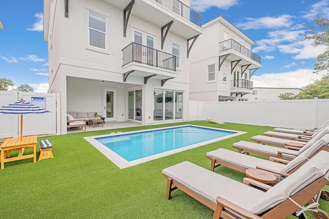 rear view of house with a patio area, a fenced in pool, a lawn, and an outdoor hangout area