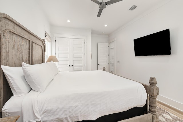 bedroom featuring ceiling fan, a closet, crown molding, and light wood-type flooring