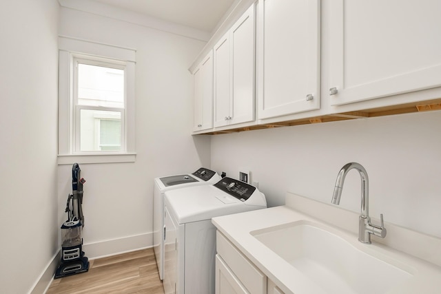 washroom featuring crown molding, sink, light wood-type flooring, washer and clothes dryer, and cabinets