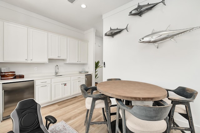 kitchen with sink, white cabinetry, stainless steel refrigerator, and light hardwood / wood-style flooring