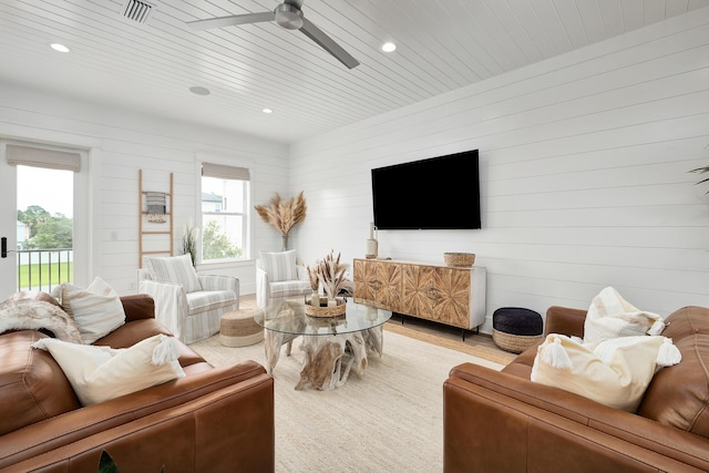 living room with ceiling fan, wood walls, wood ceiling, and a healthy amount of sunlight