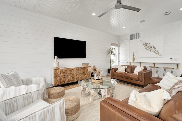 living room with ceiling fan, wooden walls, and wooden ceiling