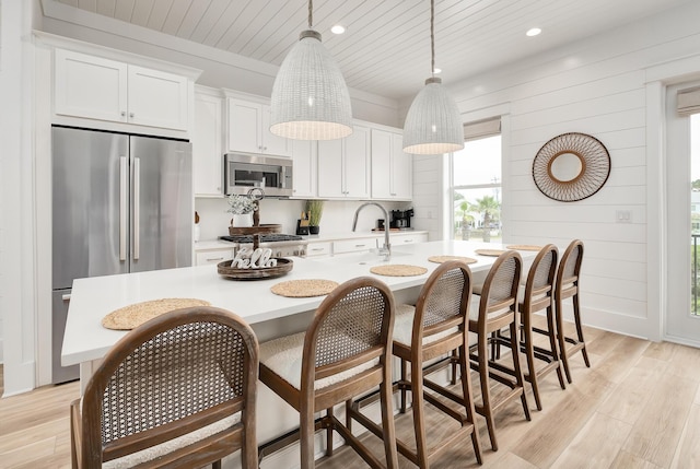 kitchen featuring white cabinetry, pendant lighting, a center island with sink, and stainless steel appliances