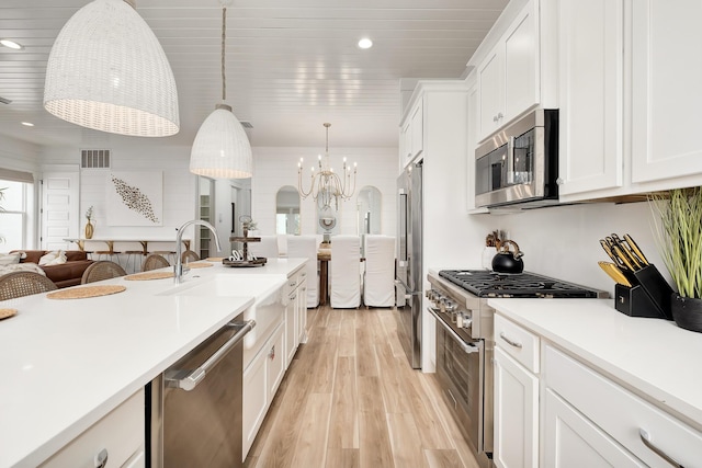 kitchen featuring light hardwood / wood-style floors, white cabinetry, hanging light fixtures, an inviting chandelier, and high quality appliances