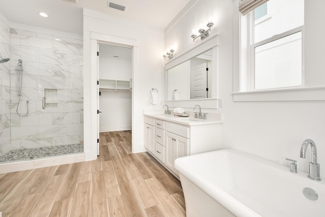 bathroom with hardwood / wood-style floors, vanity, and shower with separate bathtub