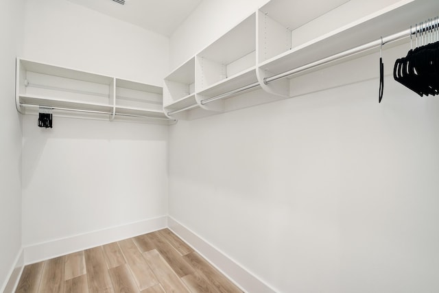 walk in closet with light hardwood / wood-style floors