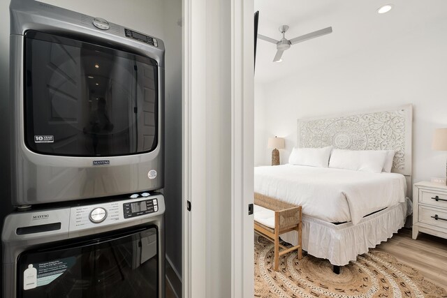 laundry area featuring light hardwood / wood-style floors, stacked washer / dryer, and ceiling fan