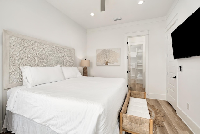 bedroom featuring ceiling fan, light hardwood / wood-style flooring, and a spacious closet