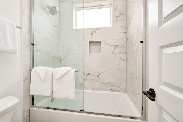 bathroom with combined bath / shower with glass door and toilet