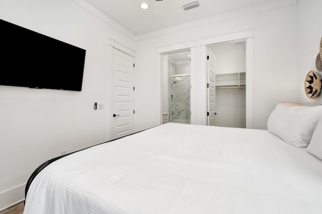 bedroom featuring a closet, connected bathroom, a spacious closet, and crown molding