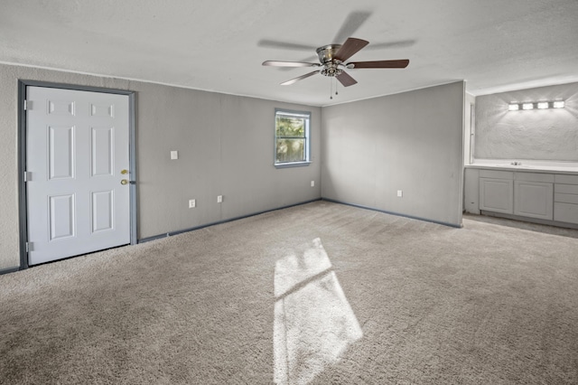 unfurnished living room with light colored carpet and ceiling fan