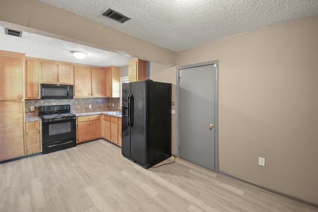 kitchen featuring light countertops, visible vents, black appliances, and light wood finished floors