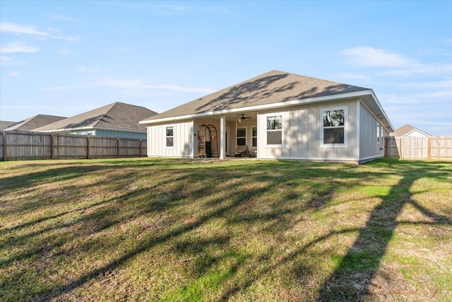 back of property featuring ceiling fan and a yard