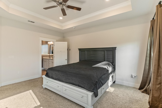 carpeted bedroom featuring ceiling fan, a tray ceiling, ornamental molding, and ensuite bathroom