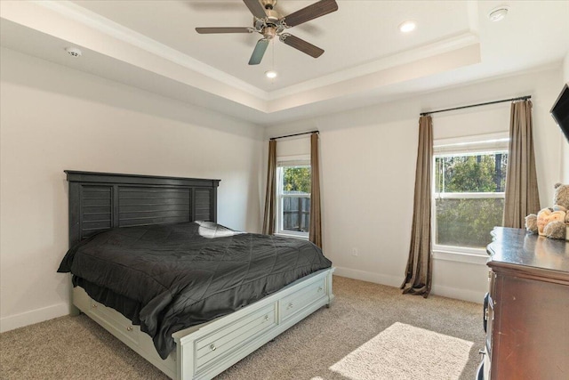 bedroom featuring light carpet, a tray ceiling, and ceiling fan