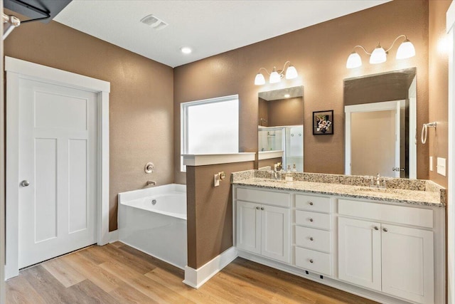 bathroom featuring hardwood / wood-style floors, vanity, and plus walk in shower