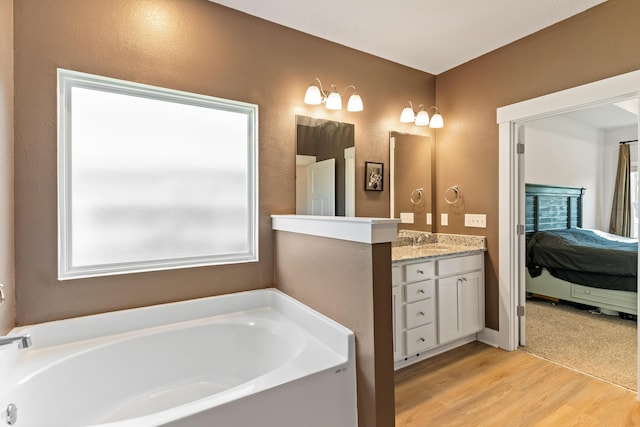 bathroom with vanity, hardwood / wood-style flooring, and a bath