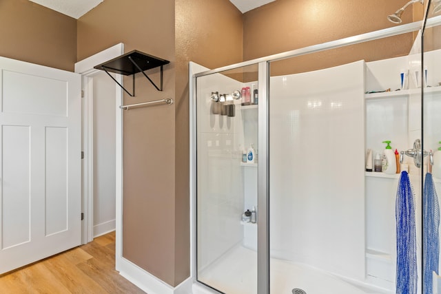 bathroom featuring wood-type flooring and a shower with door