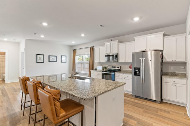 kitchen featuring a center island with sink, white cabinets, and stainless steel appliances