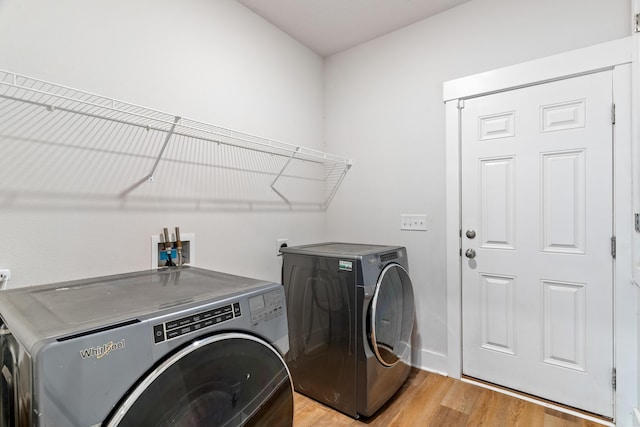 clothes washing area with washer and dryer and light hardwood / wood-style floors