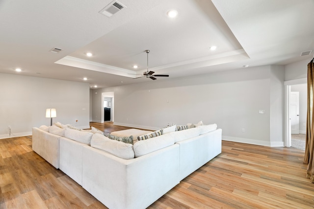 living room featuring ceiling fan, light hardwood / wood-style flooring, and a raised ceiling