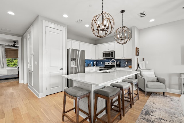 kitchen with appliances with stainless steel finishes, a breakfast bar, and white cabinets