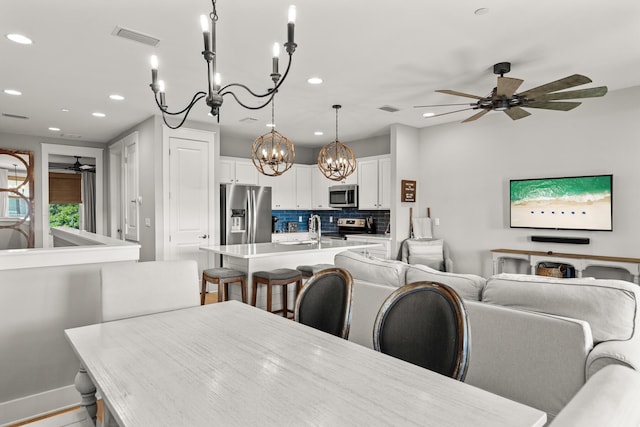 dining room with sink and ceiling fan with notable chandelier