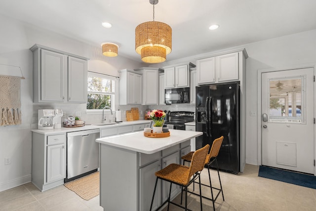 kitchen with a kitchen island, tasteful backsplash, sink, hanging light fixtures, and black appliances