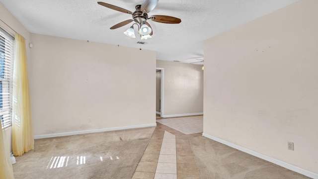 spare room with ceiling fan, light tile patterned floors, and a textured ceiling