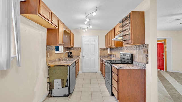 kitchen with light tile patterned flooring, appliances with stainless steel finishes, tasteful backsplash, sink, and a textured ceiling