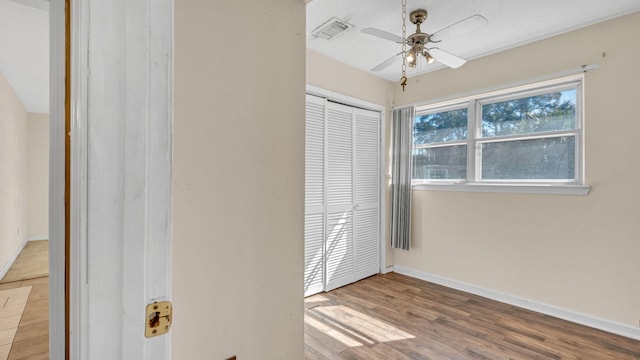 unfurnished bedroom with ceiling fan, a textured ceiling, light hardwood / wood-style floors, and a closet