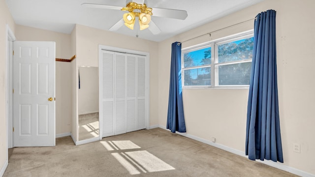 unfurnished bedroom with light colored carpet, a closet, and ceiling fan