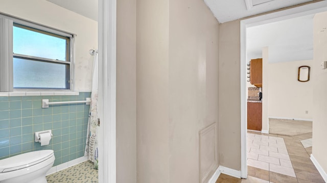 bathroom with tile patterned flooring, tile walls, and toilet