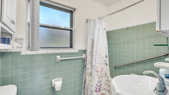 bathroom with toilet, sink, tile walls, and a shower with curtain