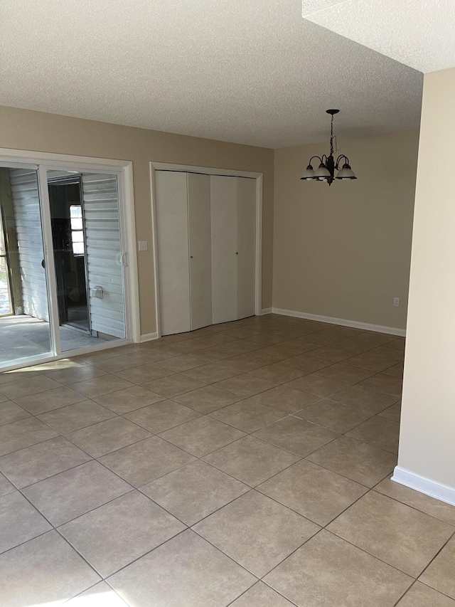 empty room featuring light tile patterned floors, a chandelier, and a textured ceiling