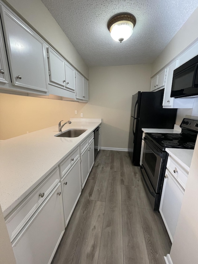 kitchen with appliances with stainless steel finishes, sink, white cabinets, dark wood-type flooring, and a textured ceiling