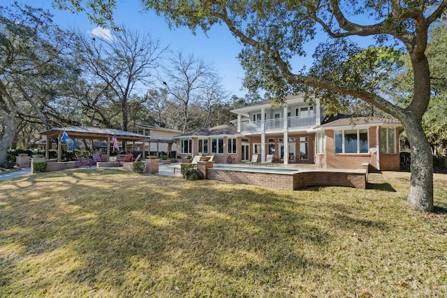 rear view of house featuring brick siding, a patio, a balcony, and a lawn