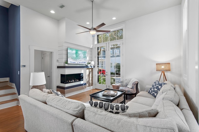 living room with a towering ceiling, hardwood / wood-style floors, and ceiling fan